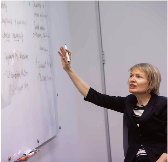 Facilitator gesturing to information on whiteboard as she speaks. 
